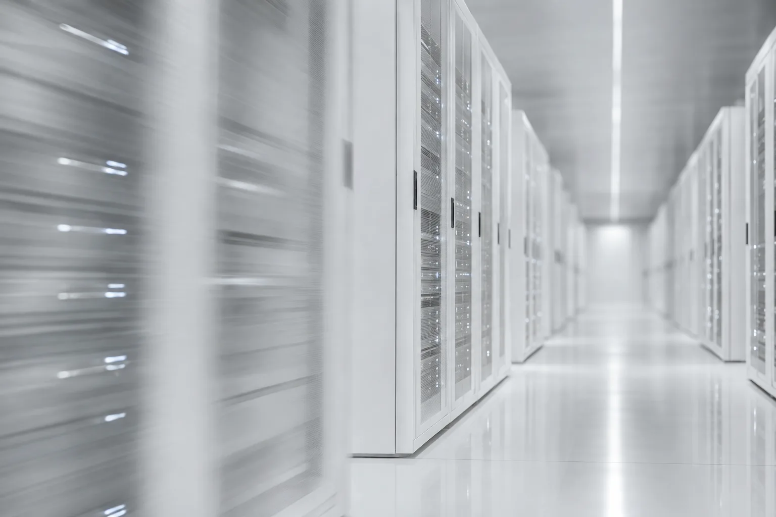 A blurred corridor of white server racks with small status lights